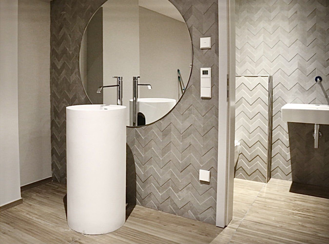 Ein Badezimmer mit zwei Waschbecken und einem runden Spiegel.