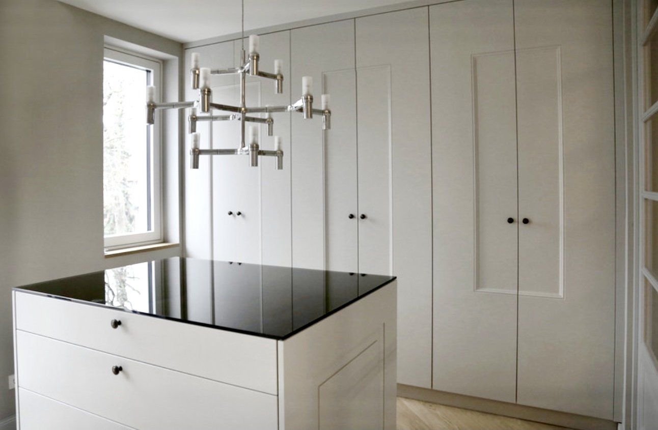 Eine Küche mit weißen Schränken und einer schwarzen Arbeitsplatte