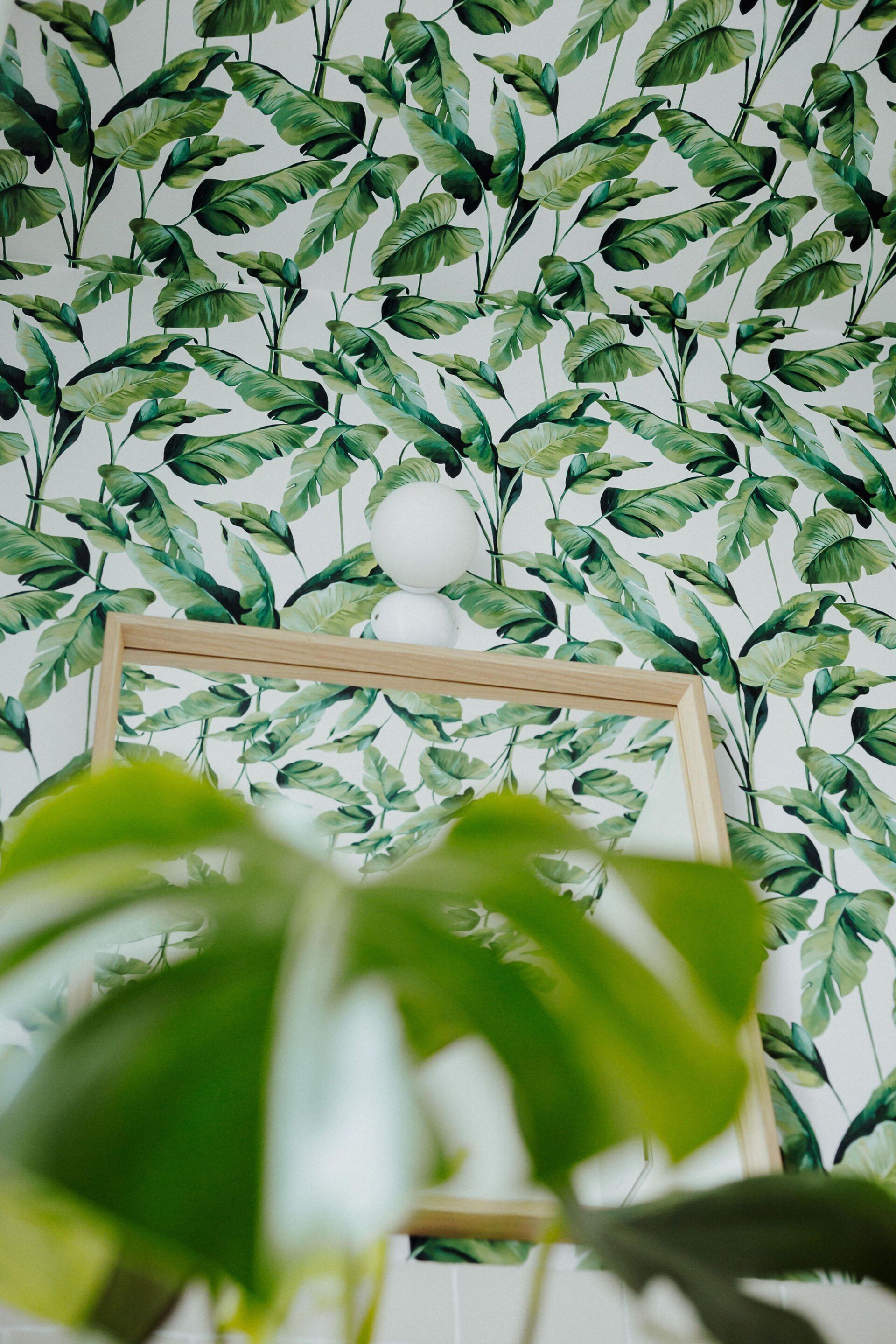 Vor einer Wand steht ein Bilderrahmen mit grünen Blättern darauf.