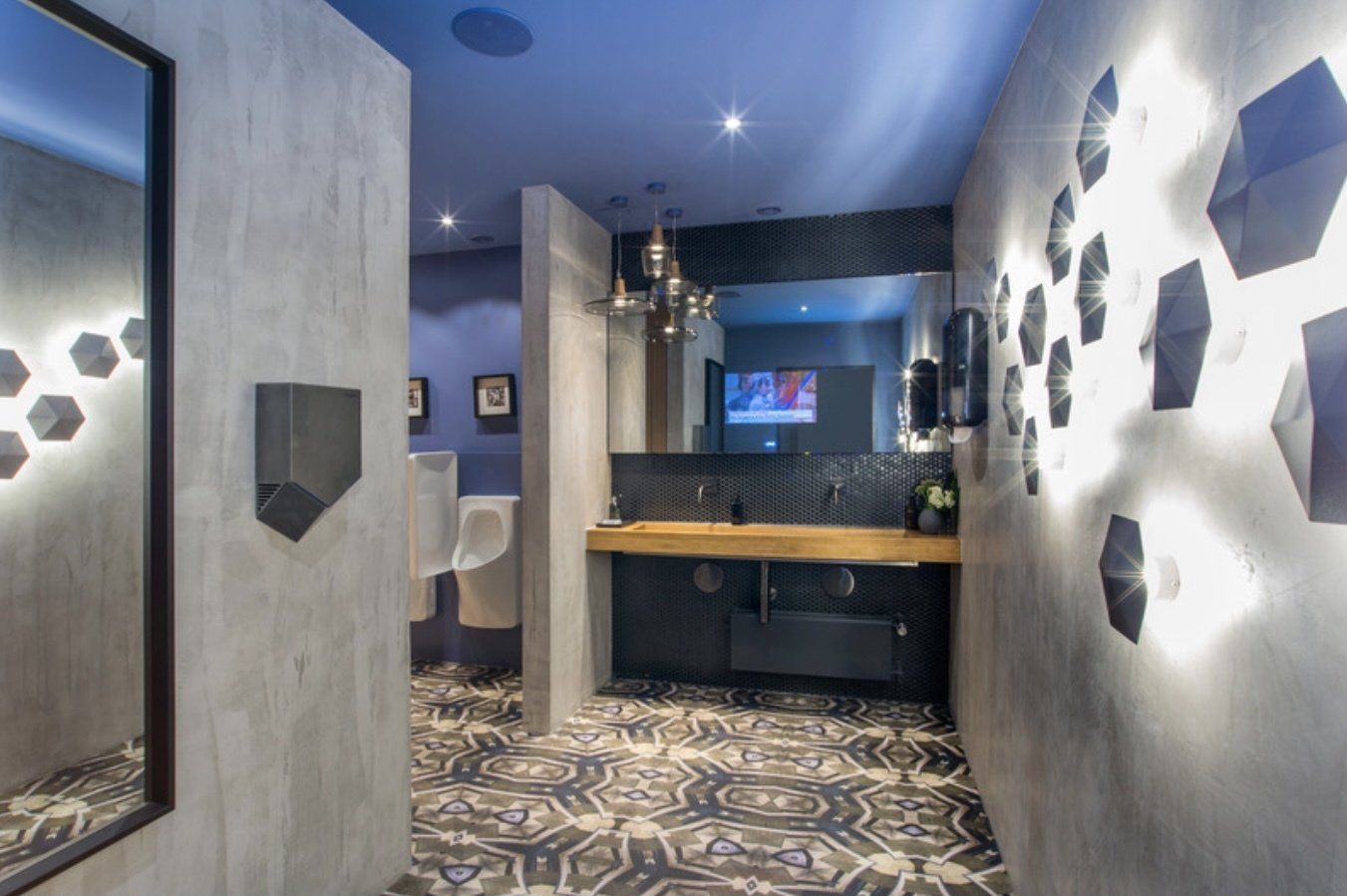 Ein Badezimmer mit Waschbecken, Spiegel und Fernseher an der Wand.