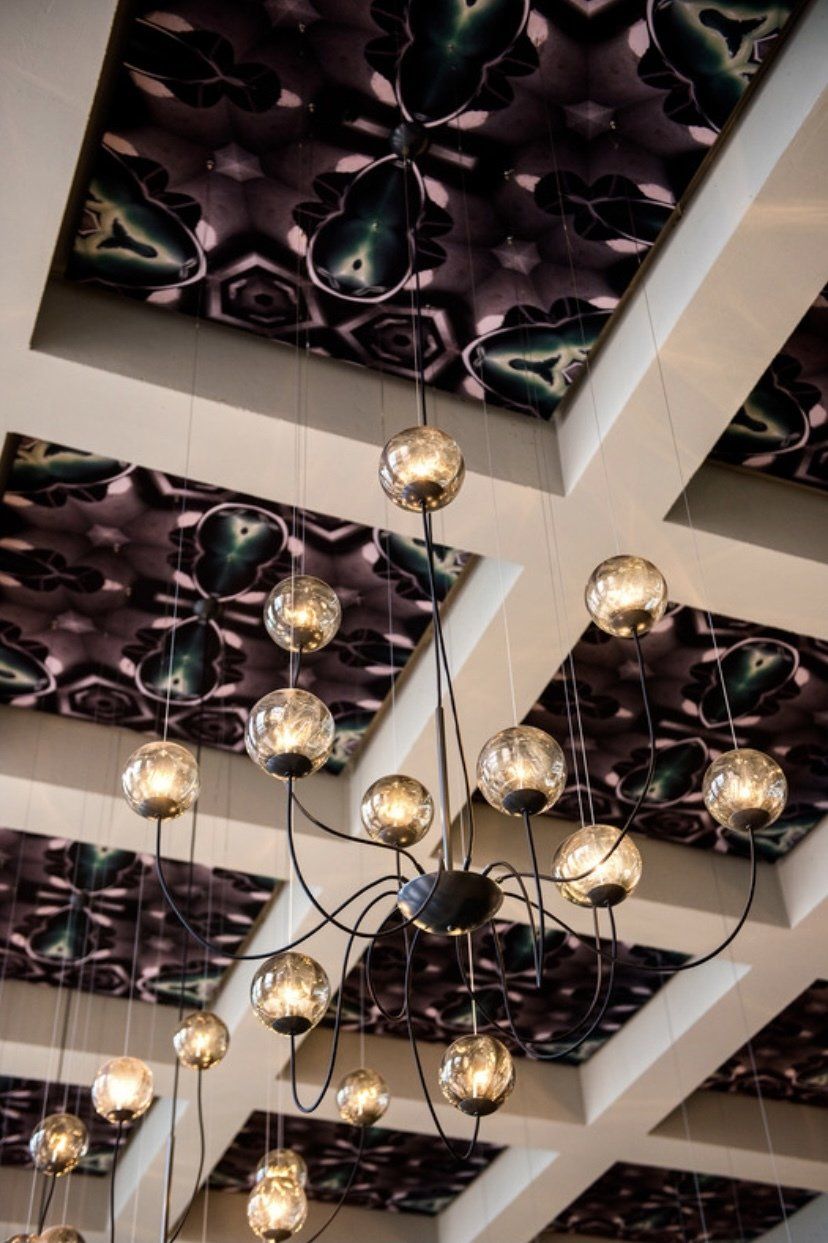 Ein Kronleuchter hängt von der Decke eines Raums mit gemusterter Decke.