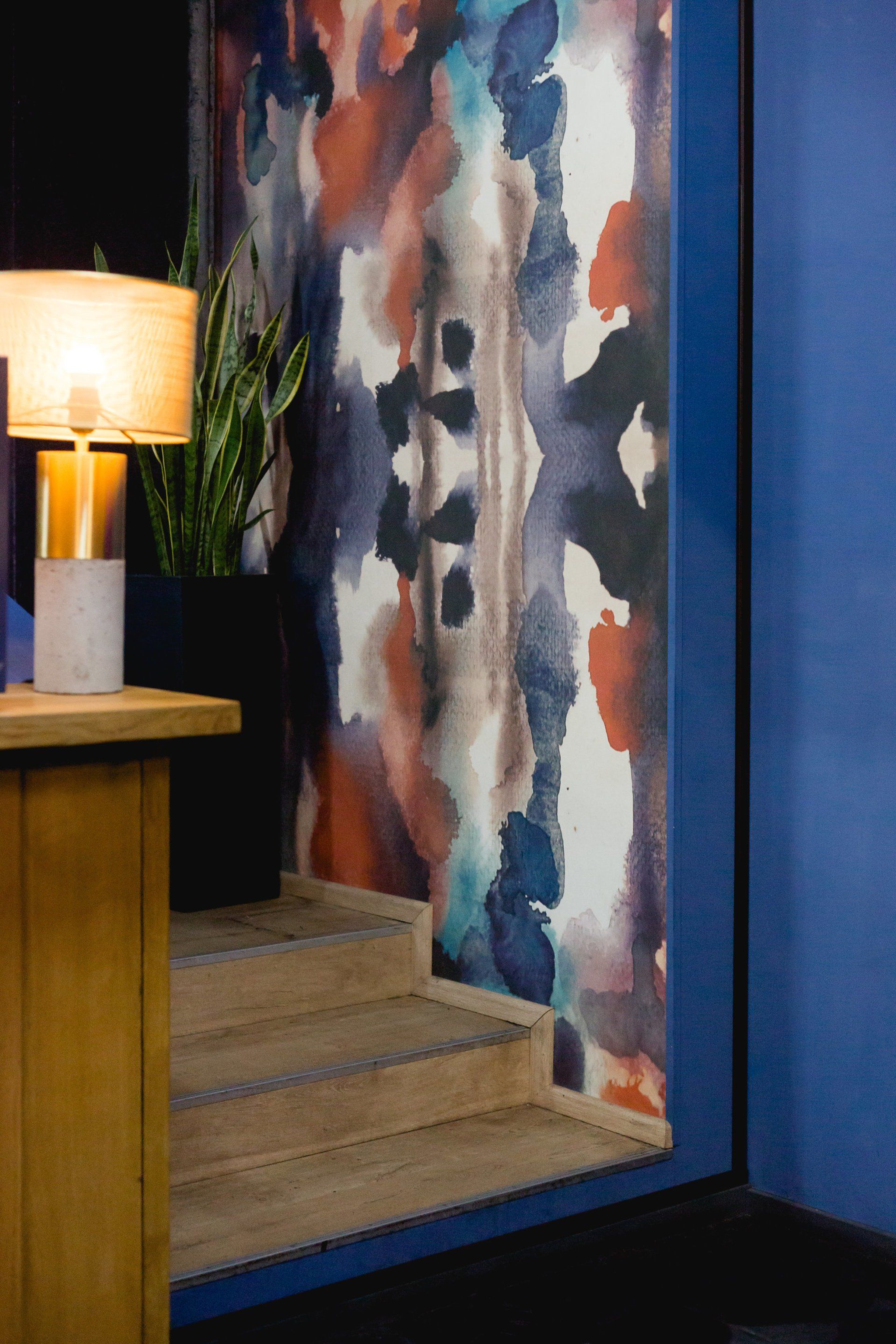 Eine Lampe steht auf einem Tisch vor einer bunten Wand