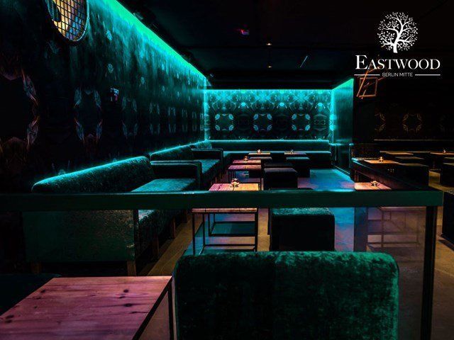 Ein dunkler Raum mit Tischen und Stühlen und einem Schild mit der Aufschrift „Eastwood“