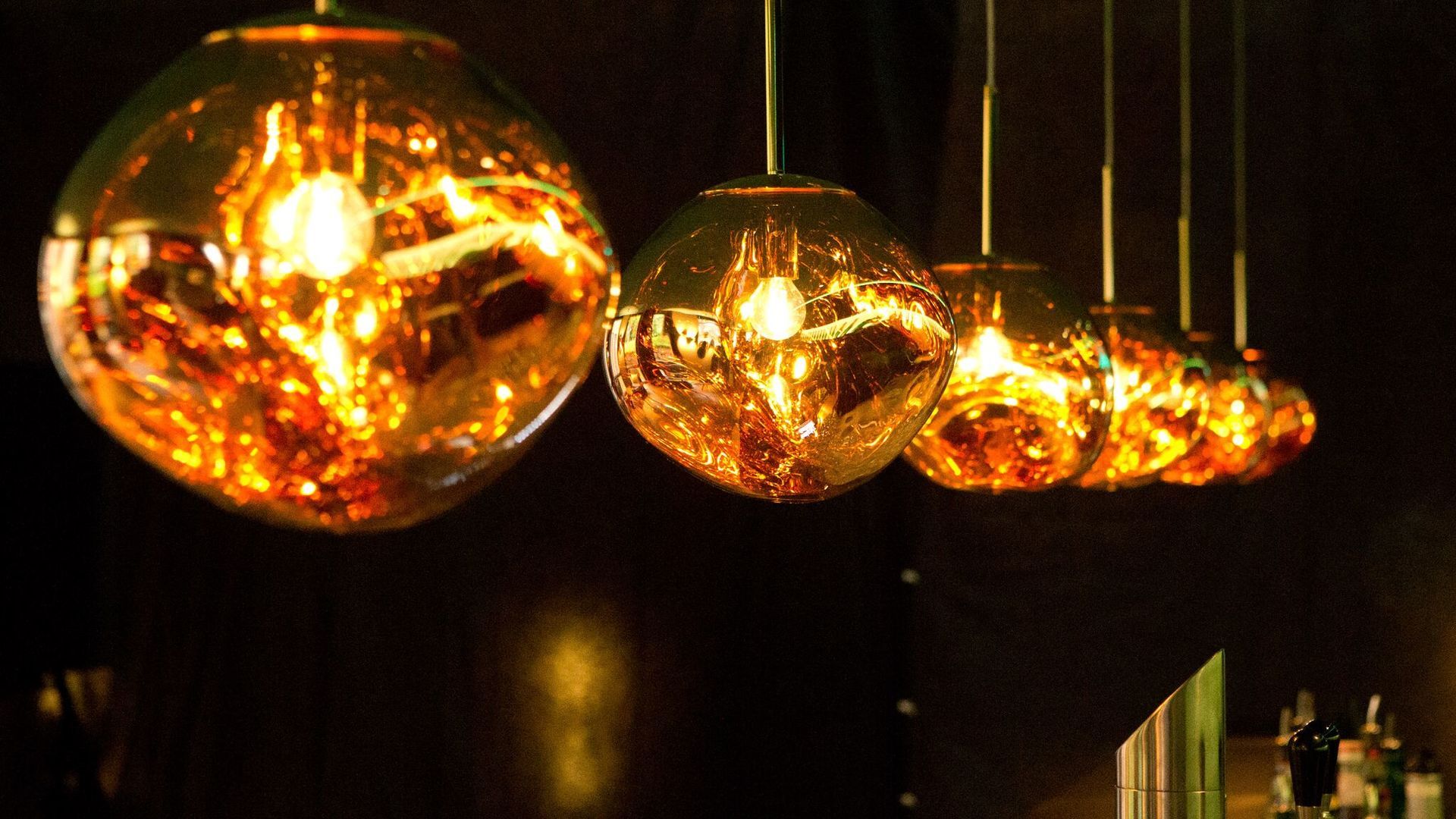 Eine Reihe von Lampen, die in einem dunklen Raum von der Decke hängen.