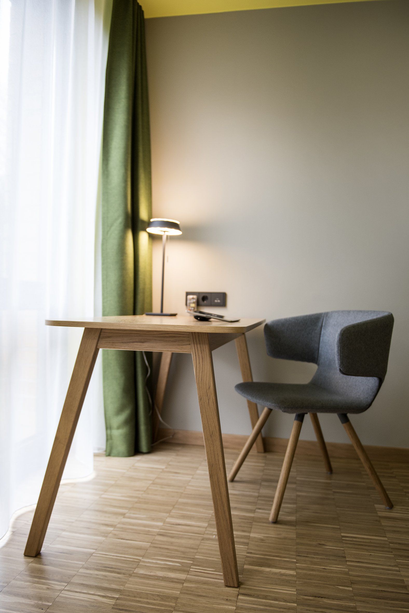 In einem Zimmer steht ein Stuhl neben einem Holzschreibtisch.