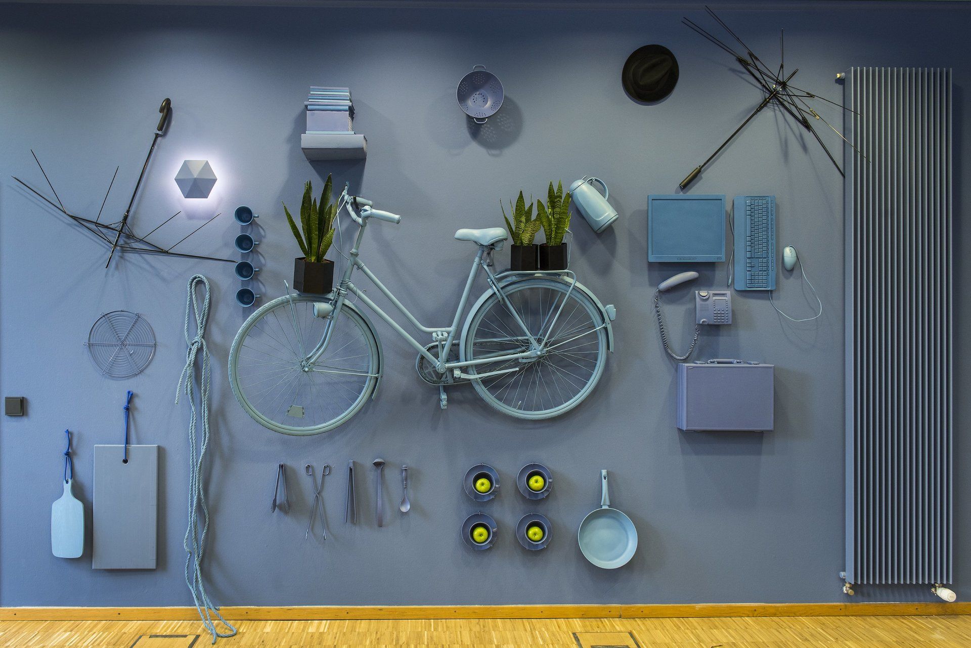 Ein Fahrrad hängt, umgeben von verschiedenen Gegenständen, an einer Wand.