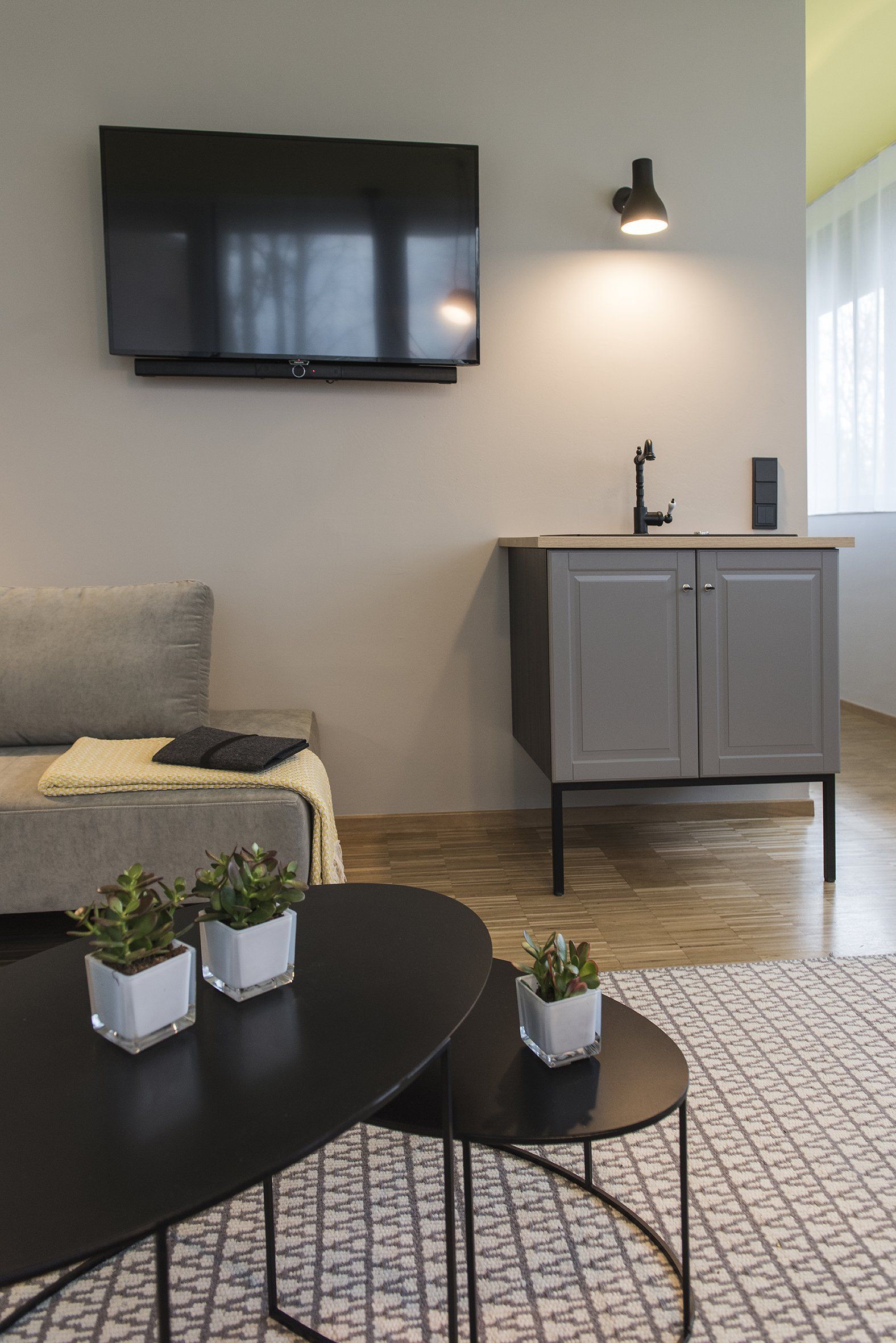 Ein Wohnzimmer mit einer Couch, zwei Tischen, einem Fernseher und einem Waschbecken.