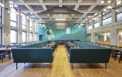 Es gibt viele Tische und Stühle im Raum.