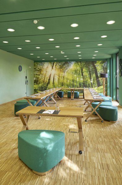 Ein Raum mit Tischen und Bänken und einem Bild von Bäumen an der Wand.