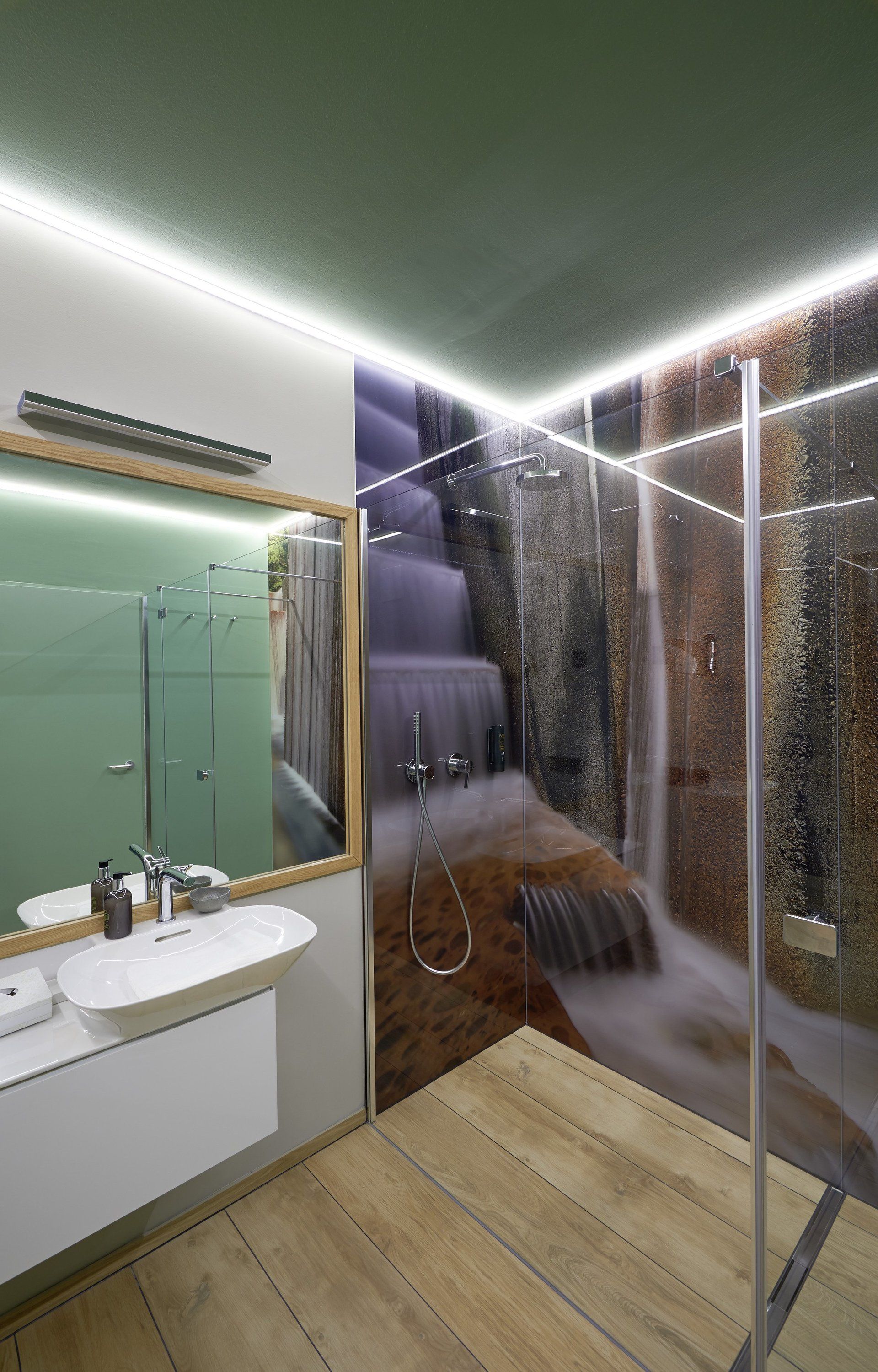 Ein Badezimmer mit Waschbecken, Spiegel, Dusche und einem Bild eines Wasserfalls an der Wand.