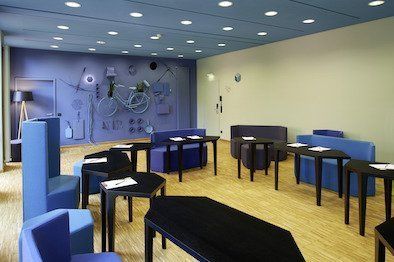 Ein Raum mit Tischen und Stühlen und einem Fahrrad an der Wand.