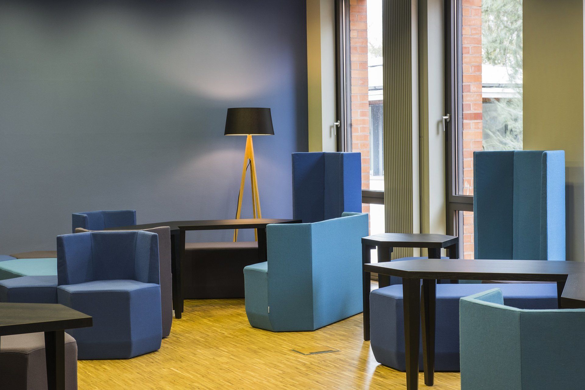 Ein Raum mit blauen Stühlen, Tischen und einer Lampe.