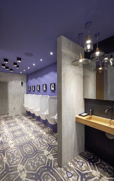 Ein Badezimmer mit violetter Decke, Urinalen und einem Waschbecken.