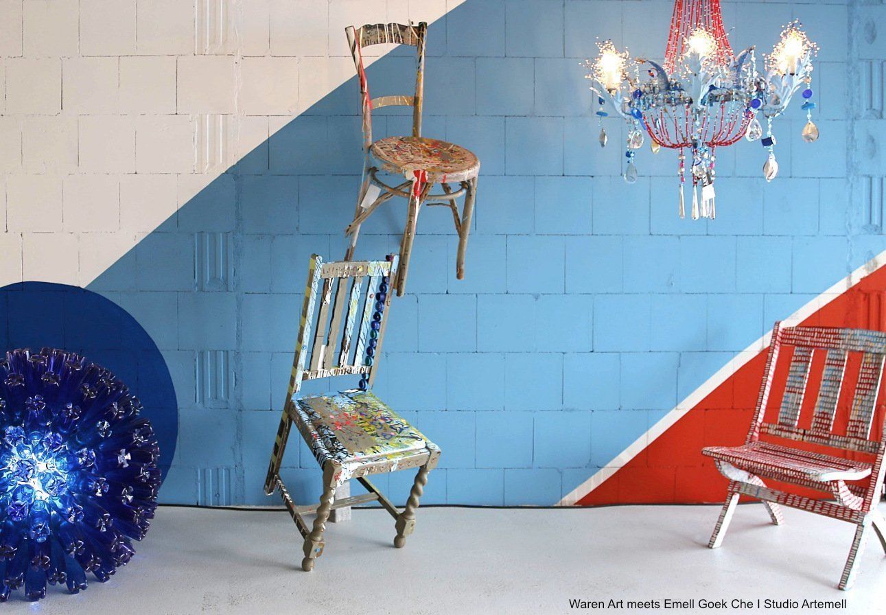 Zwei Stühle stehen vor einer blauen und roten Backsteinwand.