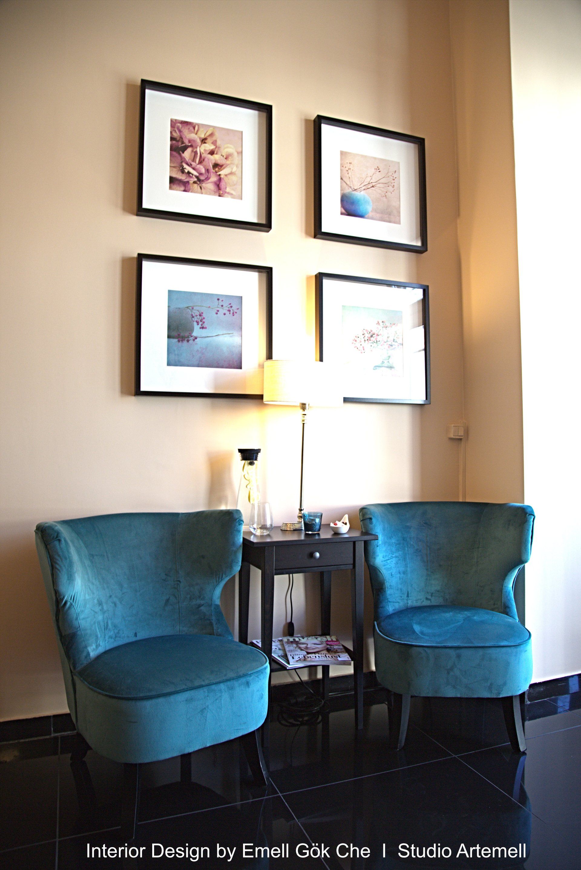 Zwei blaue Stühle stehen in einem Raum mit Bildern an der Wand