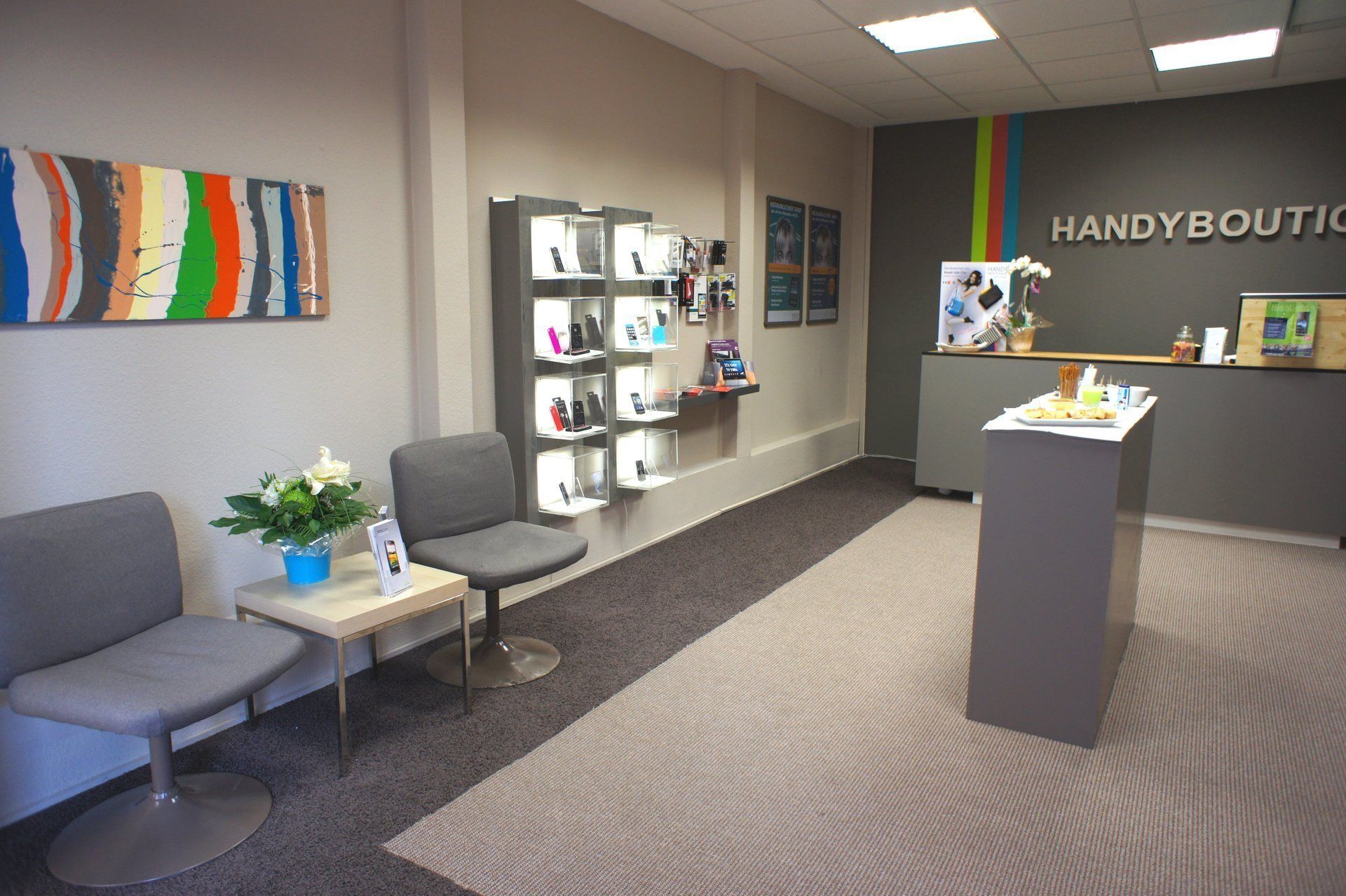 Ein Wartezimmer mit einem Tisch und Stühlen und einem Schild mit der Aufschrift „Handyboutique“
