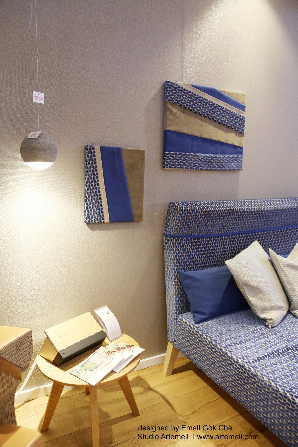 Ein Wohnzimmer mit einem blauen Sofa und zwei Gemälden an der Wand.