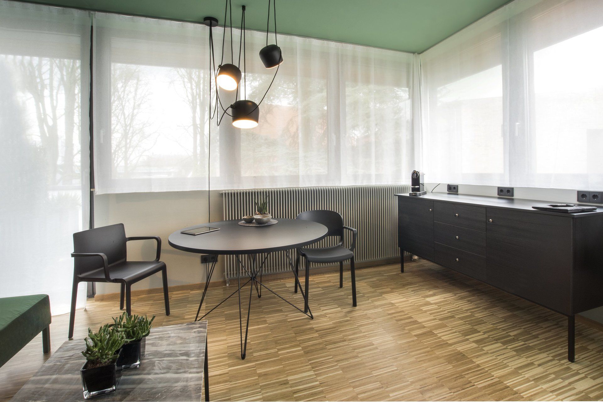 Ein Wohnzimmer mit Tisch und Stühlen und einer grünen Decke.