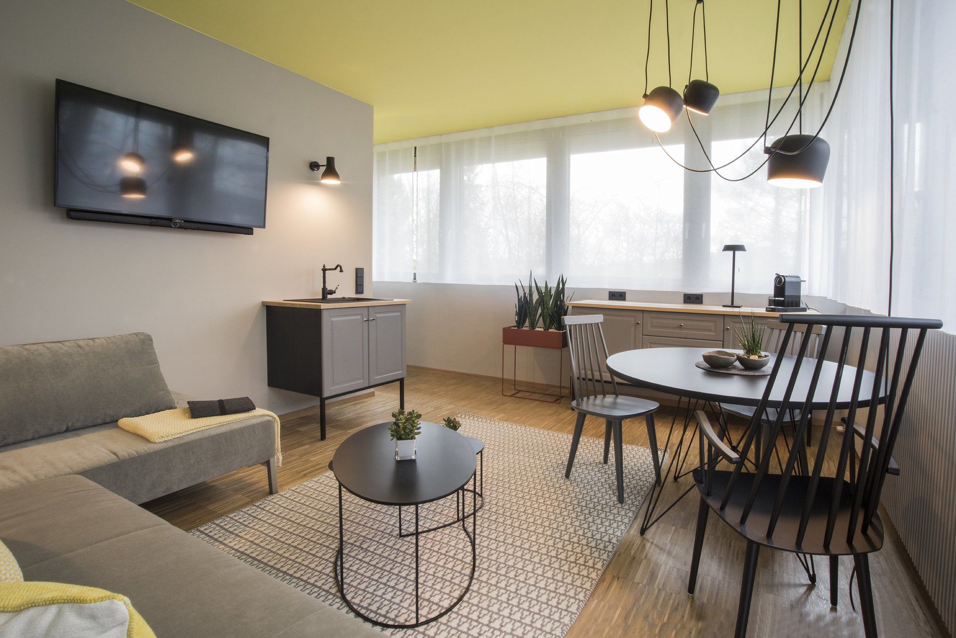 Ein Wohnzimmer mit Couch, Tisch, Stühlen und einem Flachbildfernseher.