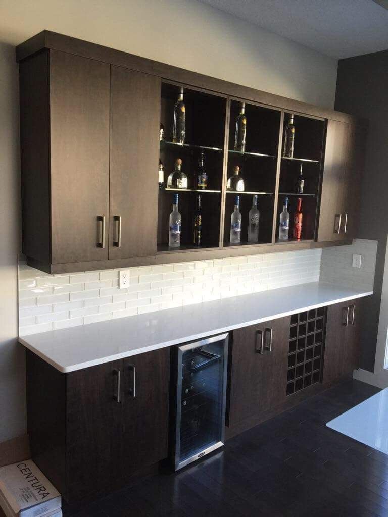 A kitchen with lots of cabinets and bottles on shelves