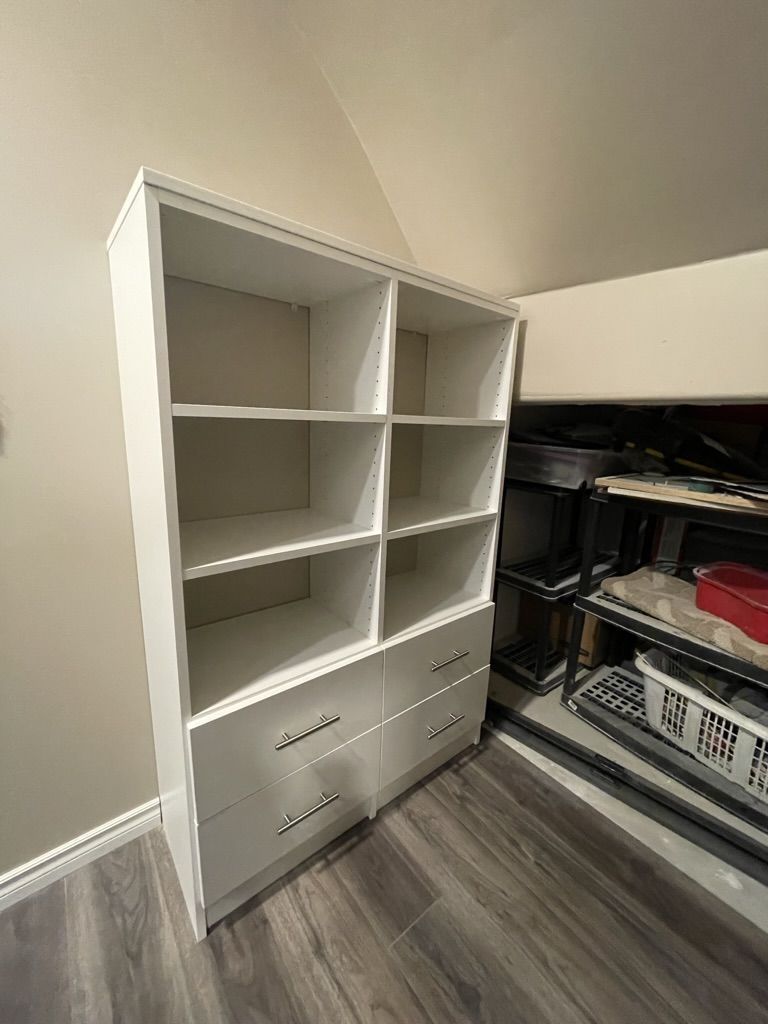 A white bookshelf with drawers and shelves in a closet.