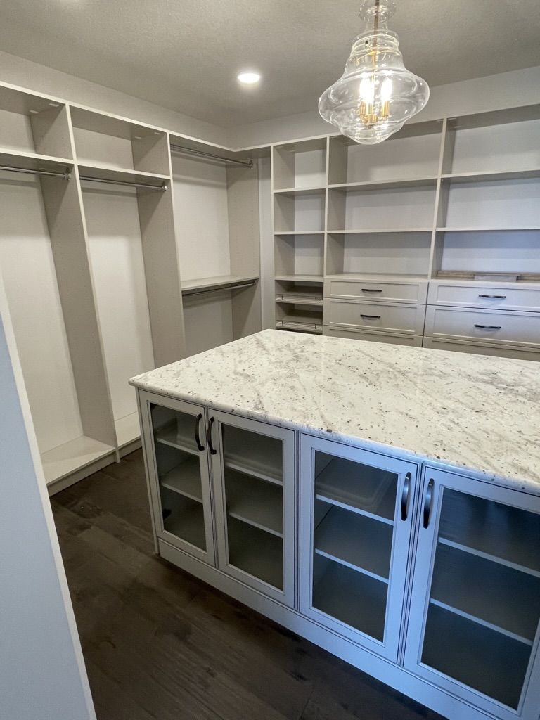A walk in closet with a large island in the middle.