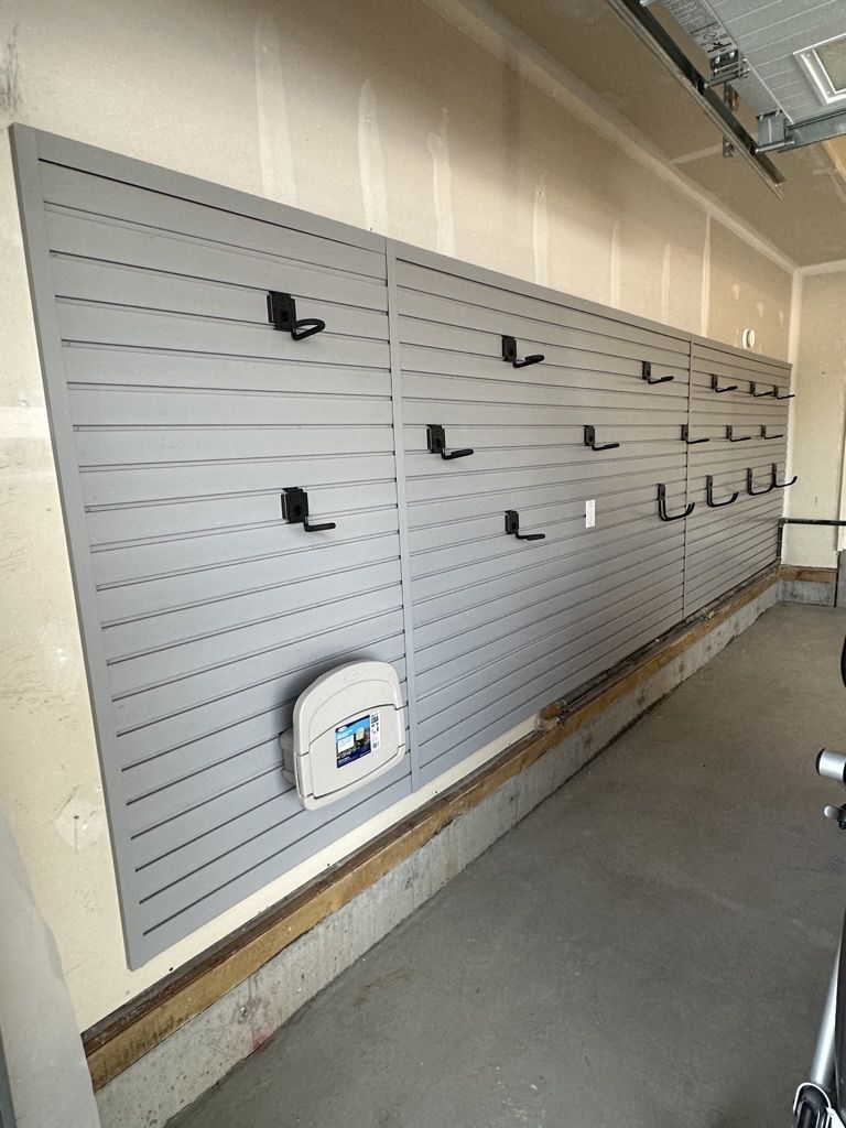 A wall with a lot of hooks on it in a garage.