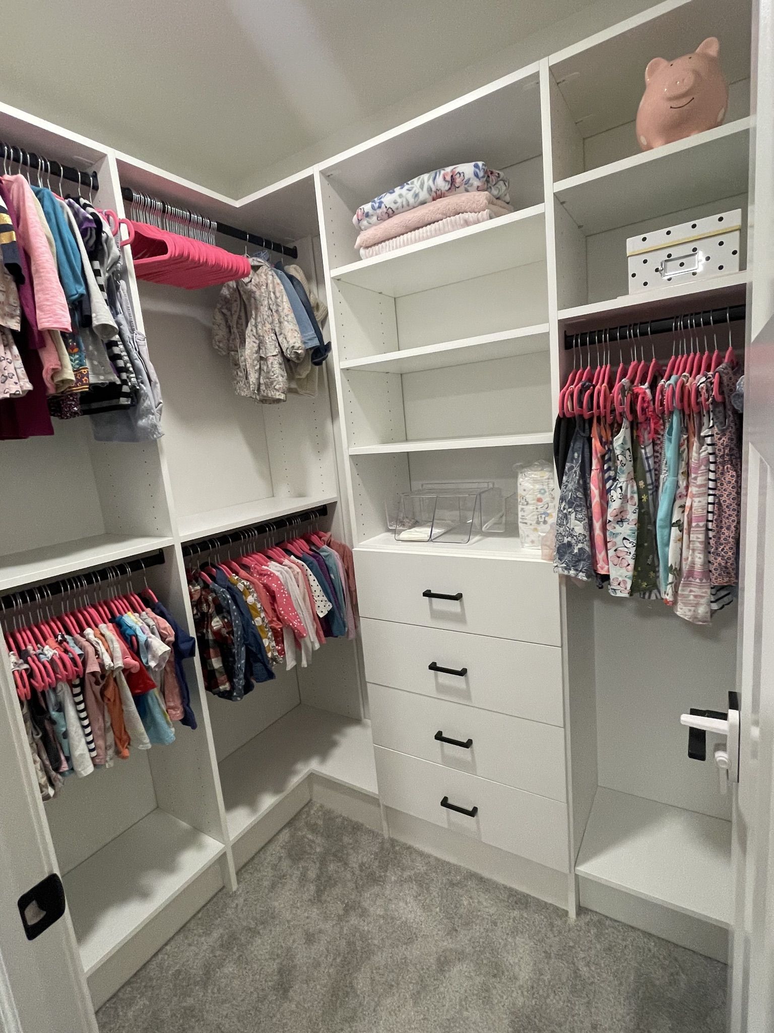 A walk in closet filled with lots of clothes and a piggy bank.