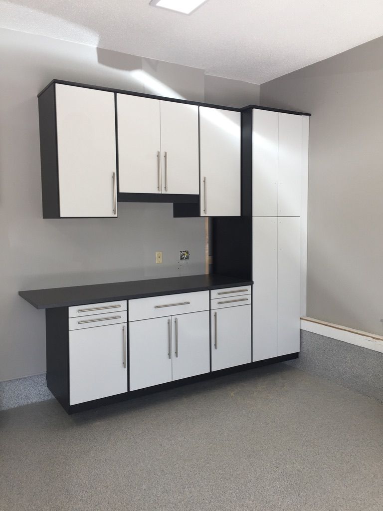 A kitchen with black and white cabinets and a refrigerator
