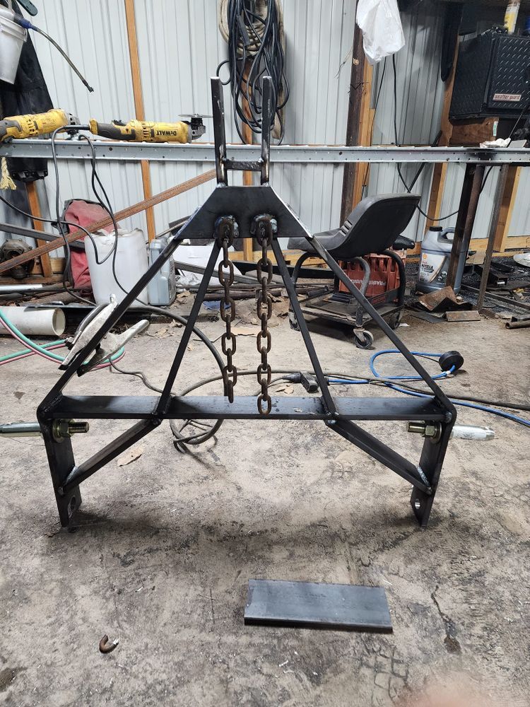 A metal object with chains attached to it is sitting on the ground in a garage.