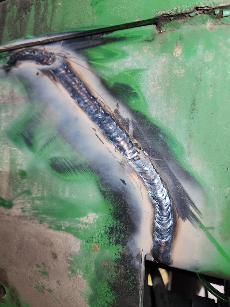 A close up of a welding joint on a green piece of metal.