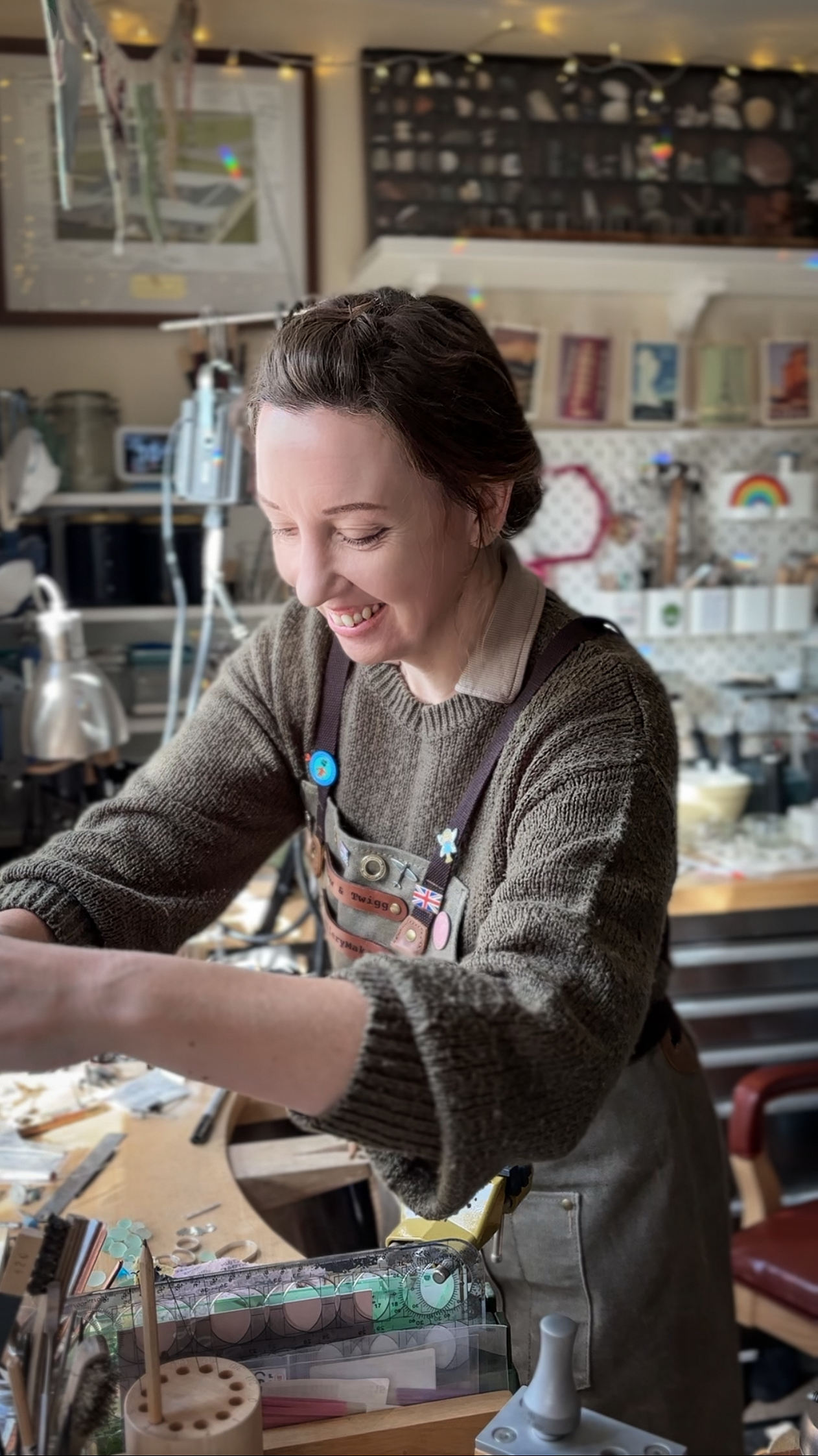 A photo of Kelly Twigg from Willow and Twigg Jewellery, in her workshop wearing a green canvas apron.