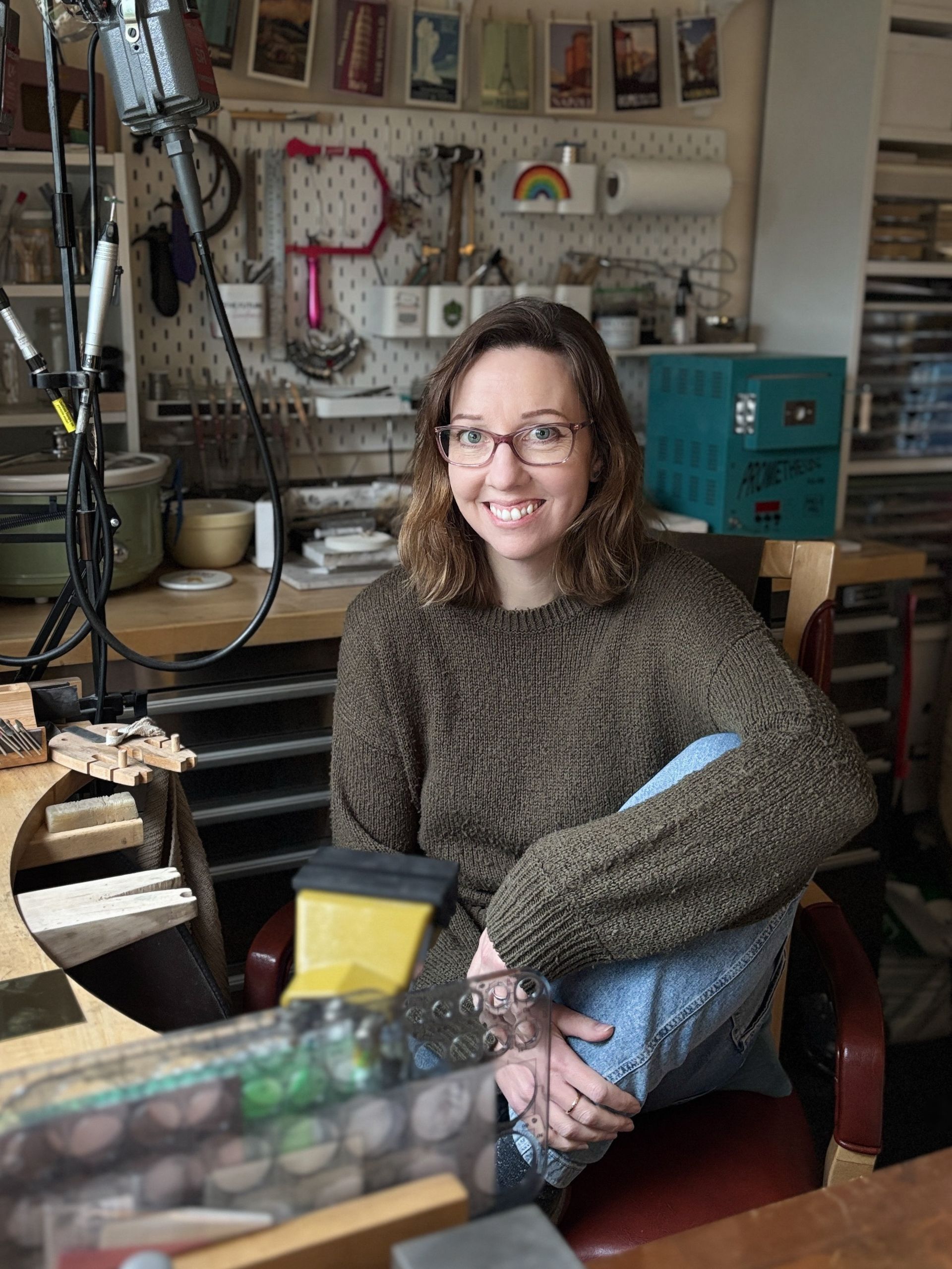 A photo of Kelly Twigg from Willow and Twigg Jewellery, in her workshop wearing a green canvas apron.
