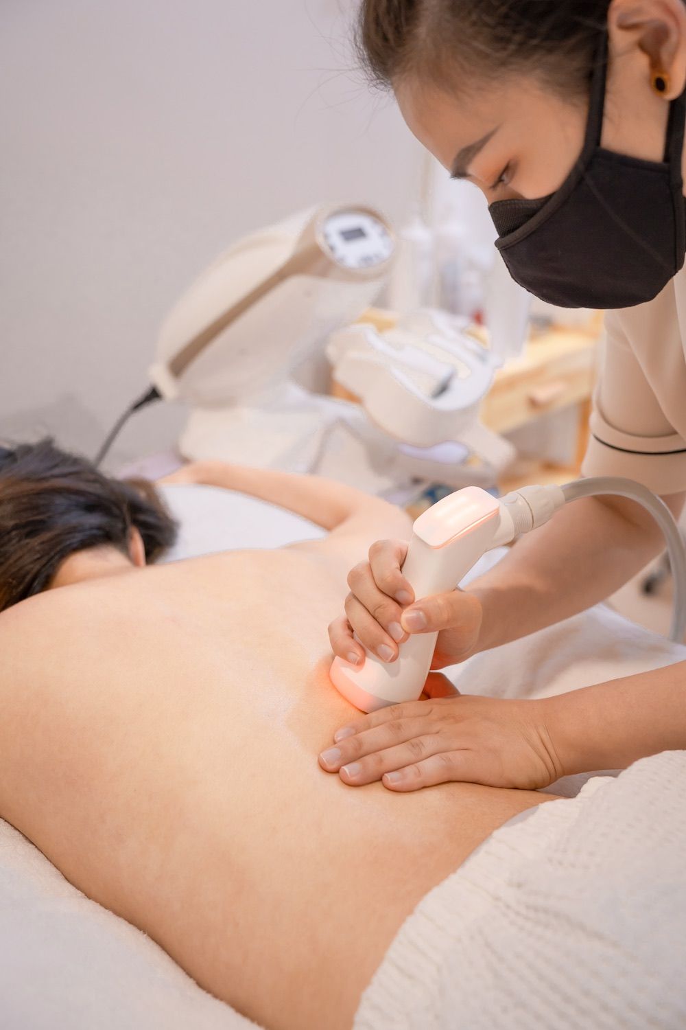 A woman wearing a mask is getting a massage on her back.