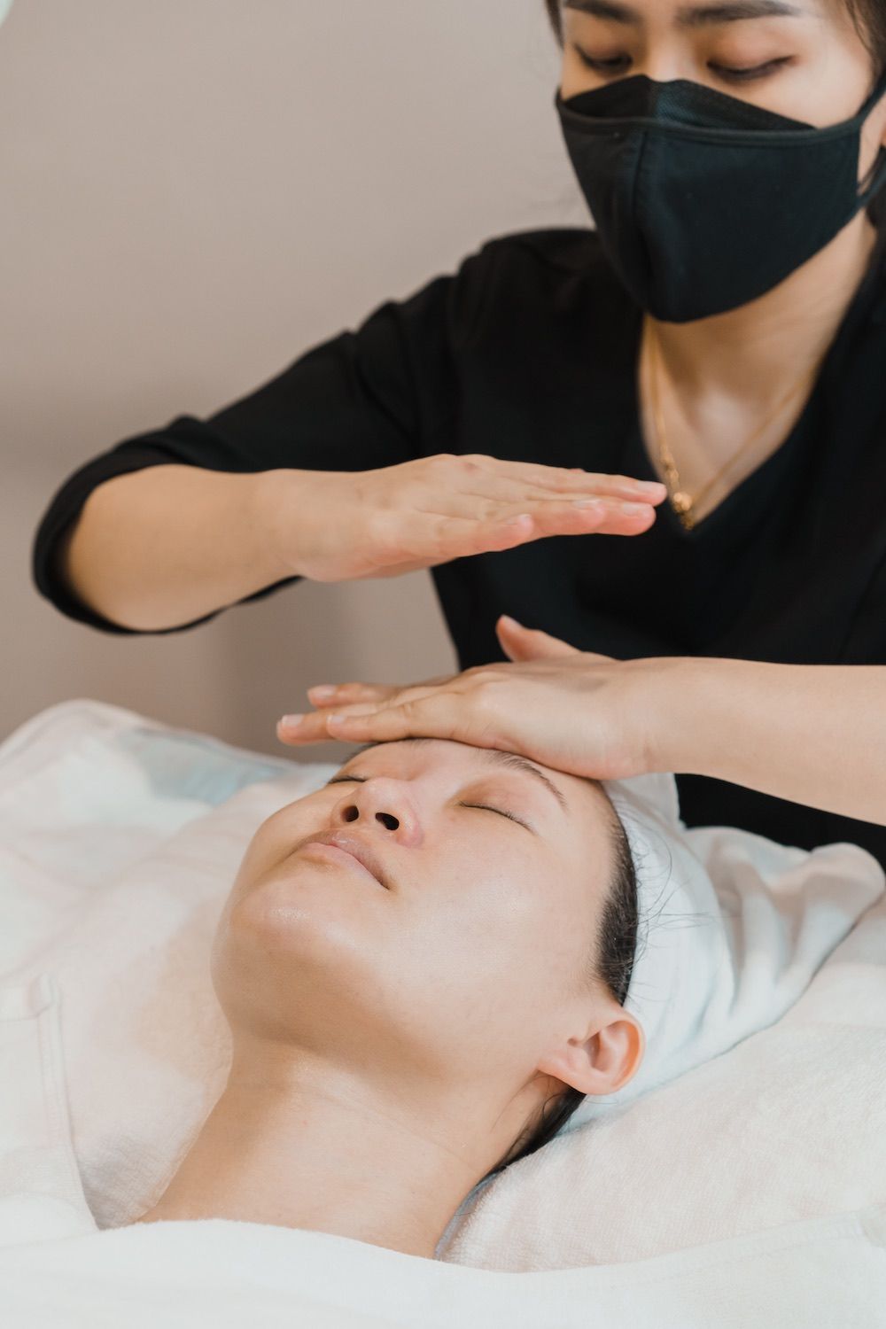 A woman wearing a mask is getting a massage on her face.