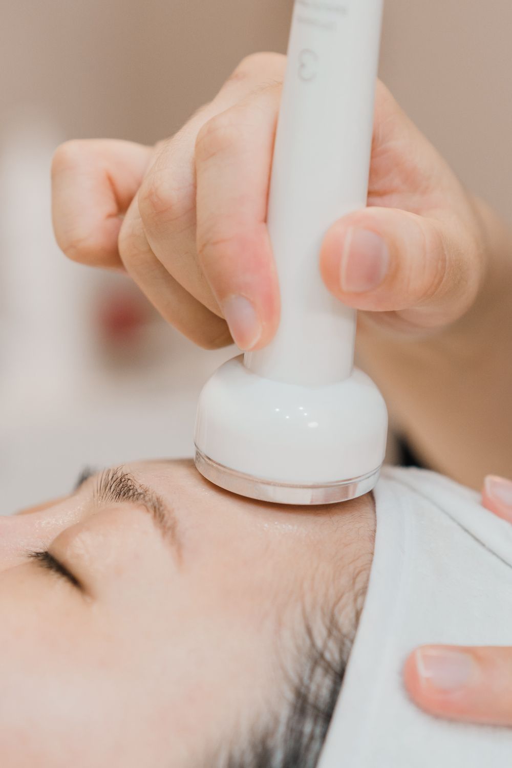 A woman is getting a facial treatment with a machine on her face.