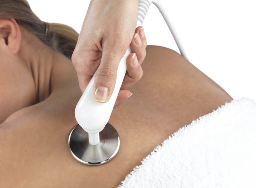 A woman is getting a massage with a machine on her back.