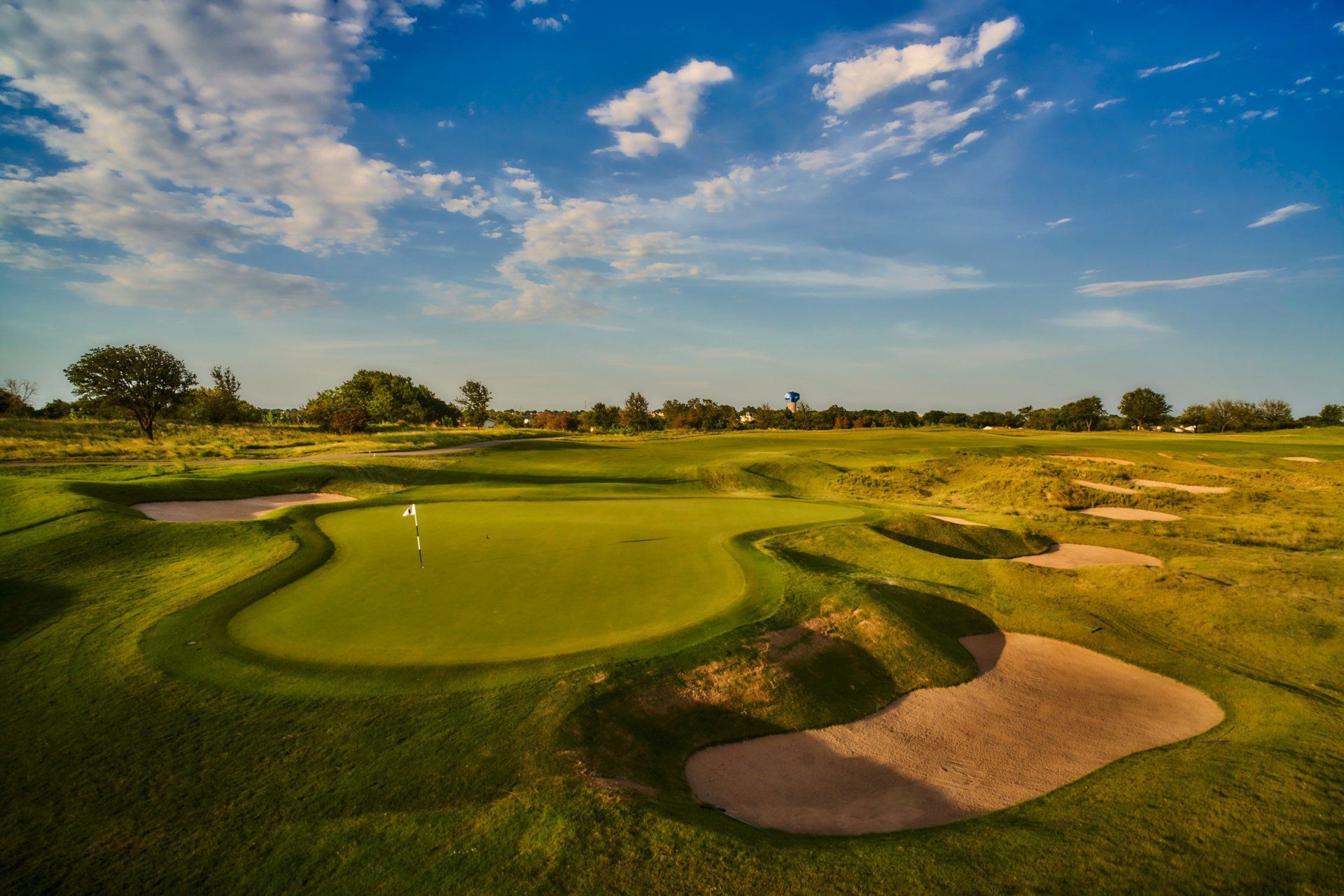An aerial view of a golf course with a green and bunkers.