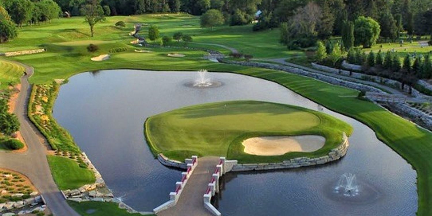 An aerial view of a golf course with a bridge over a pond.