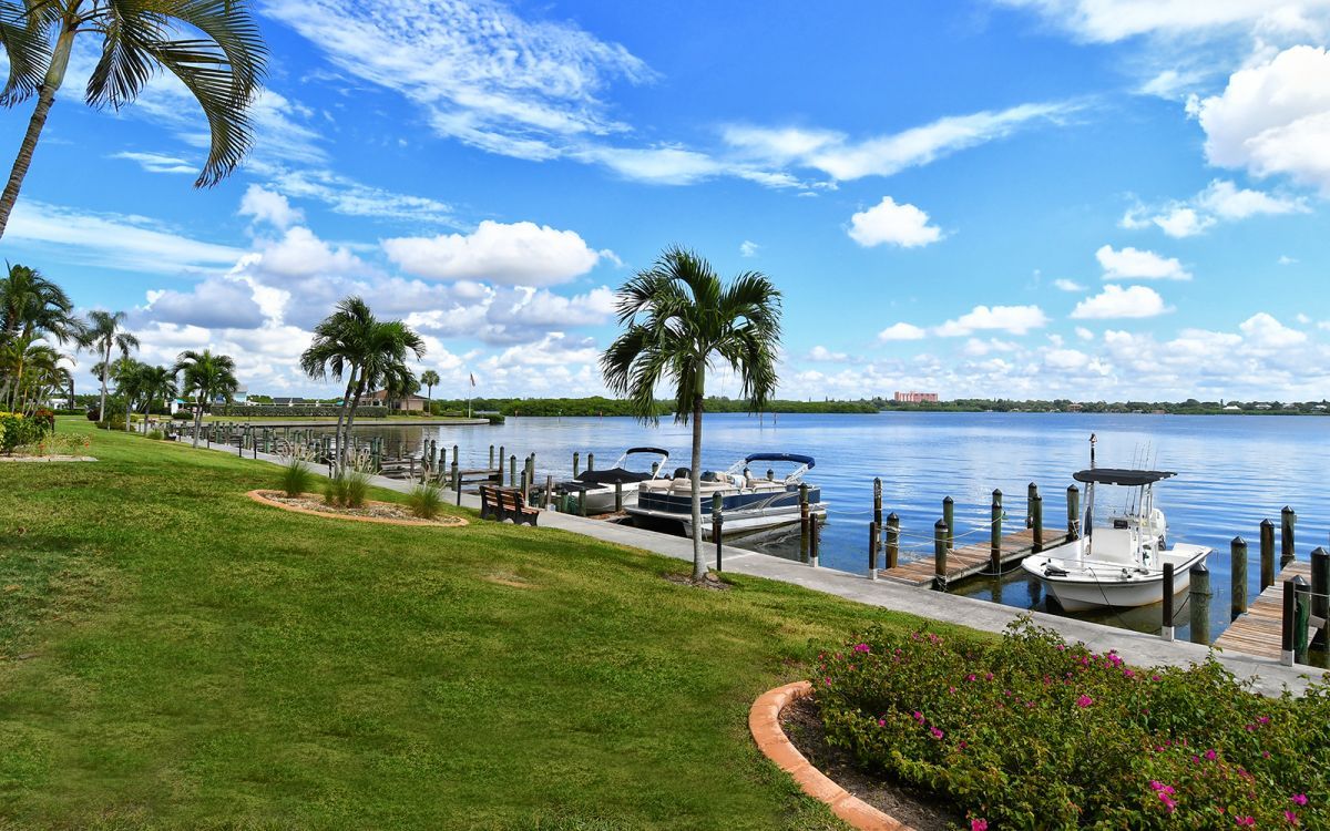Picture of dock with boats tied up to it in front of a lawn. 