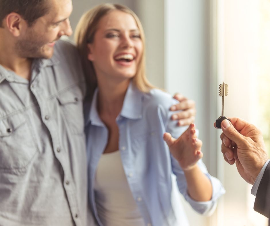 Happy couple reaching for key to home.
