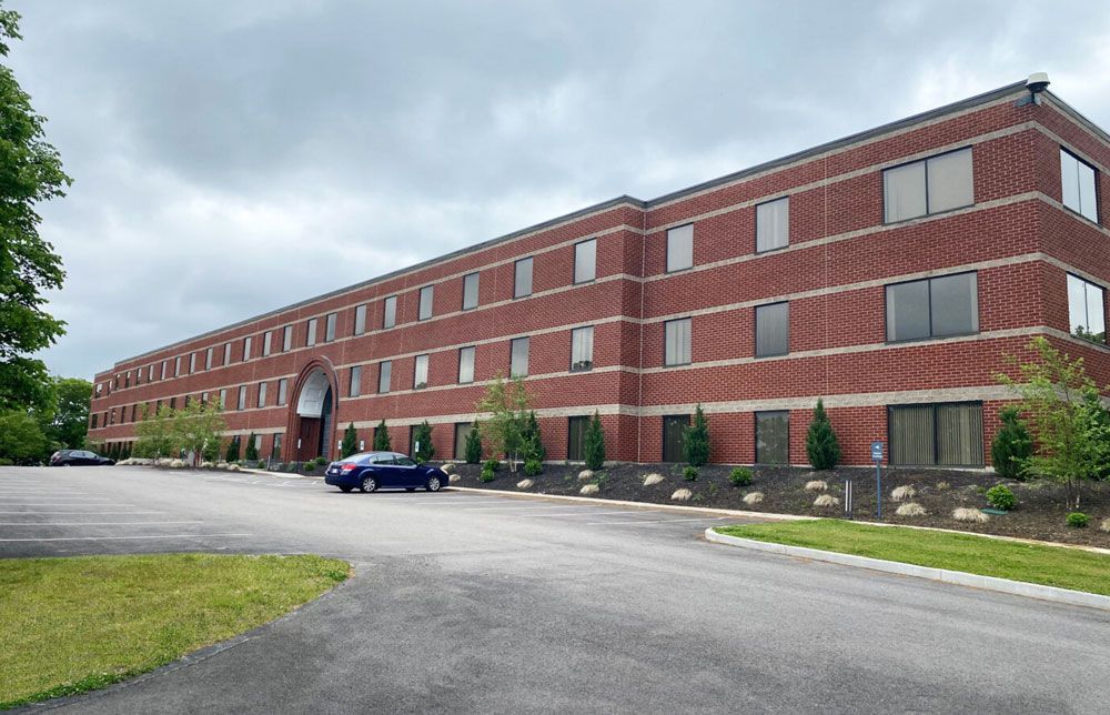 A large brick building with a blue car parked in front of it.