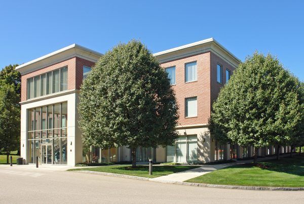 A large brick building with a lot of windows and trees in front of it
