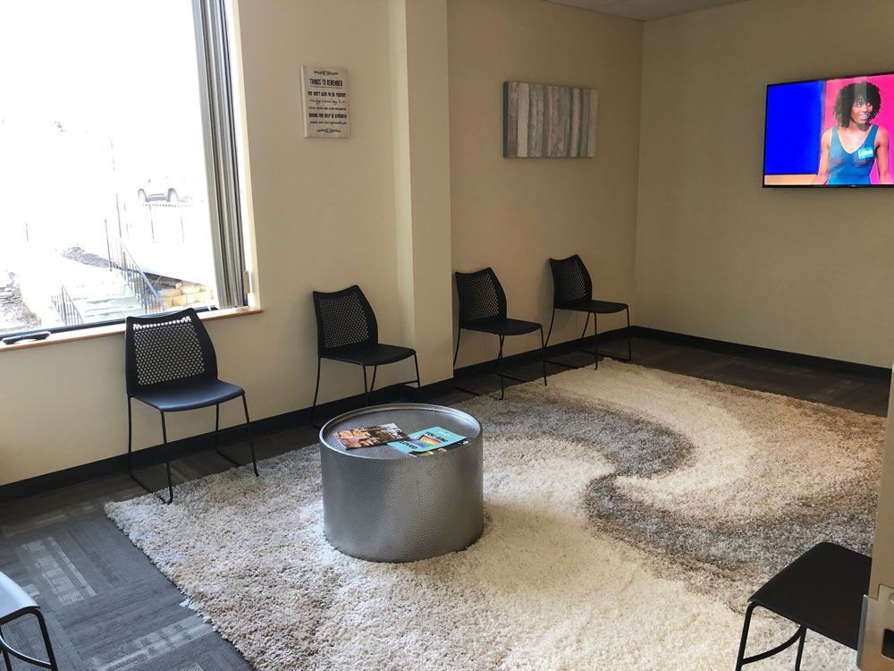 A waiting room with chairs , a table , and a television.