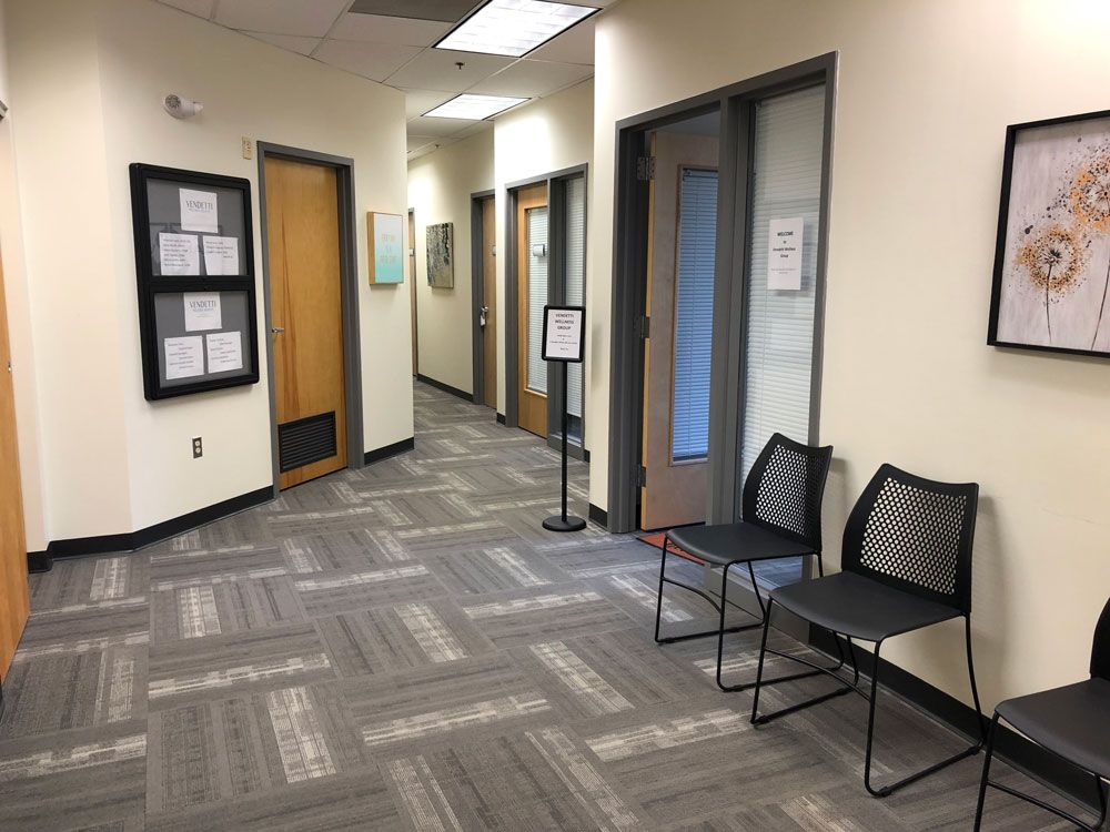 A hallway with chairs and a bulletin board on the wall.