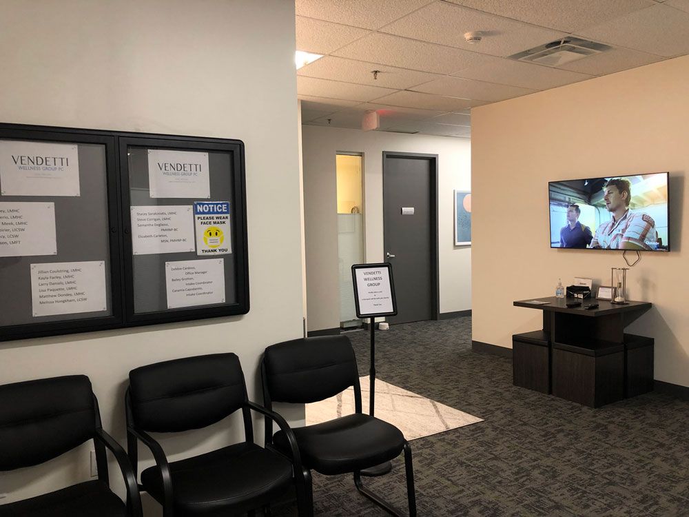A waiting room with chairs and a television on the wall.