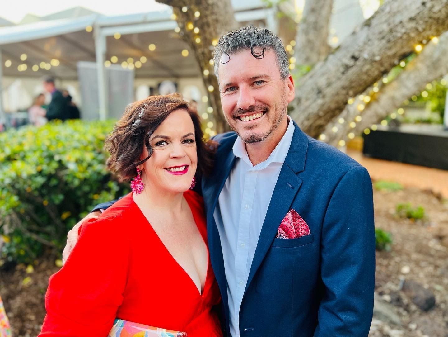 clayton menyweather in a suit and emma menyweather in a red dress are posing for a picture .
