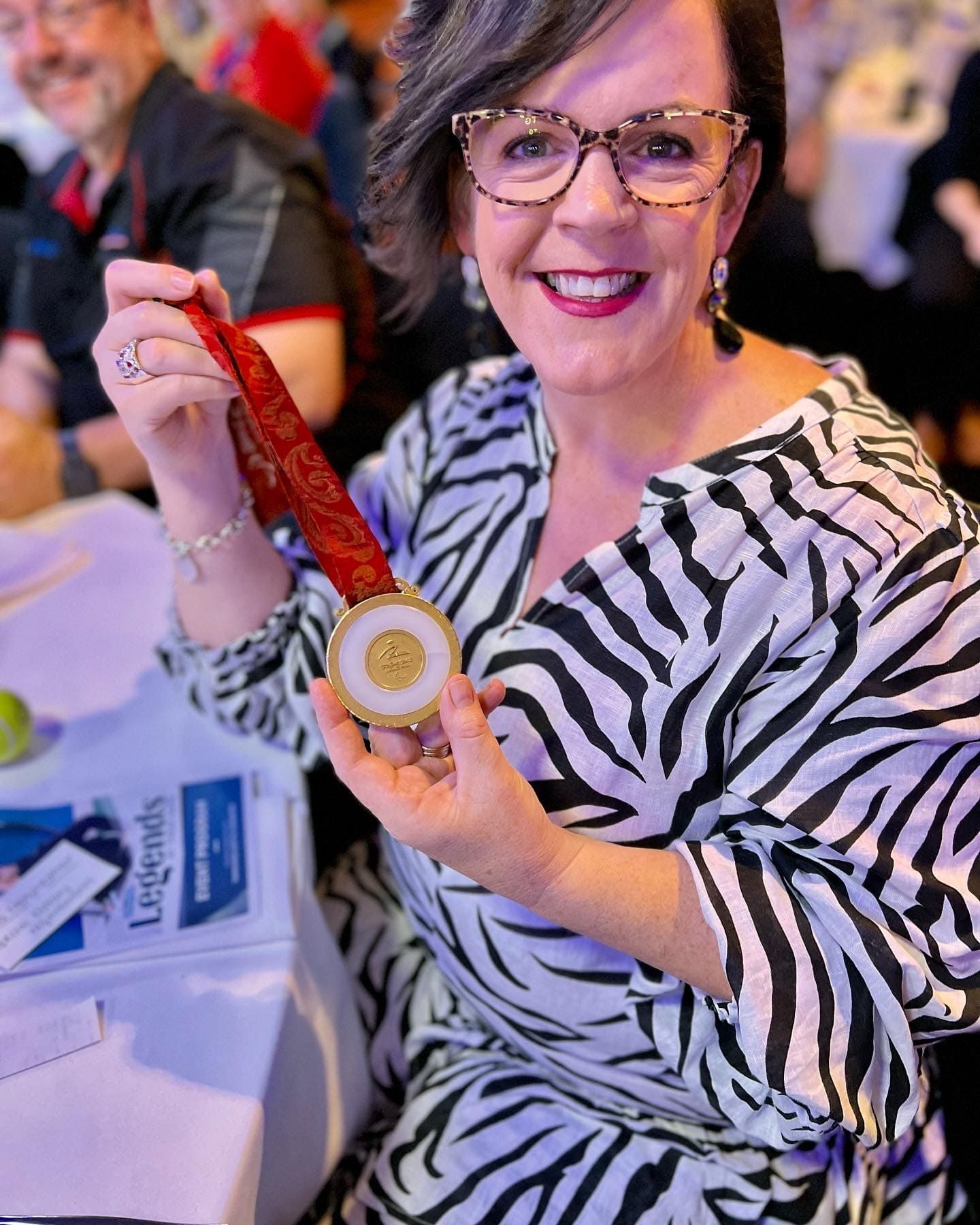 emma menyweather  in a zebra print dress is holding a medal .