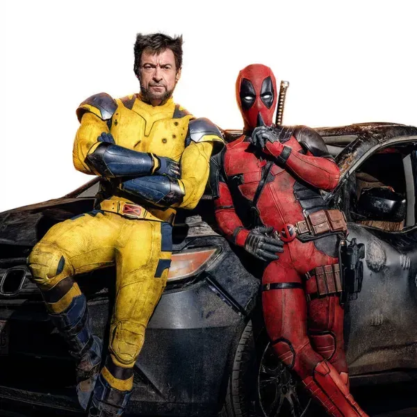 Wolverine and deadpool standing next to each other in front of a car