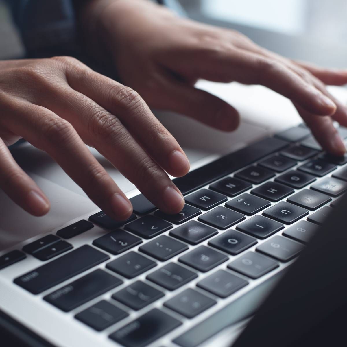 Hands typing on a laptop keyboard; close-up view.